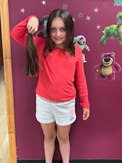 A child with a red blouse and a stuff toy beside her