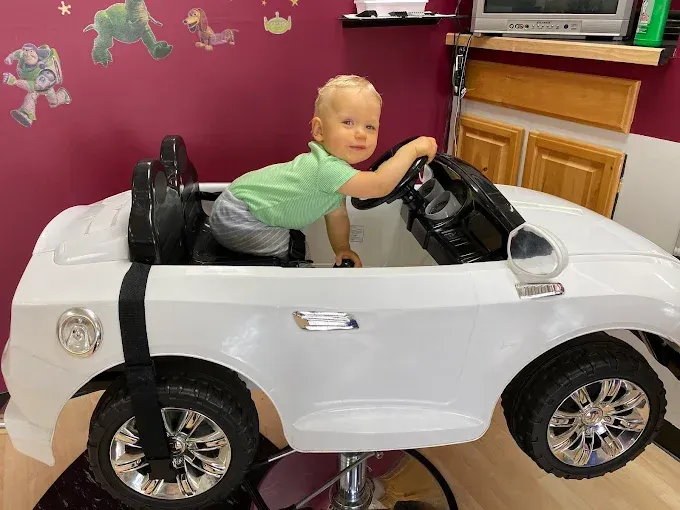 A little boy is sitting in a toy car.
