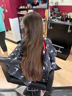 A woman with very long hair is sitting in a chair in a salon.