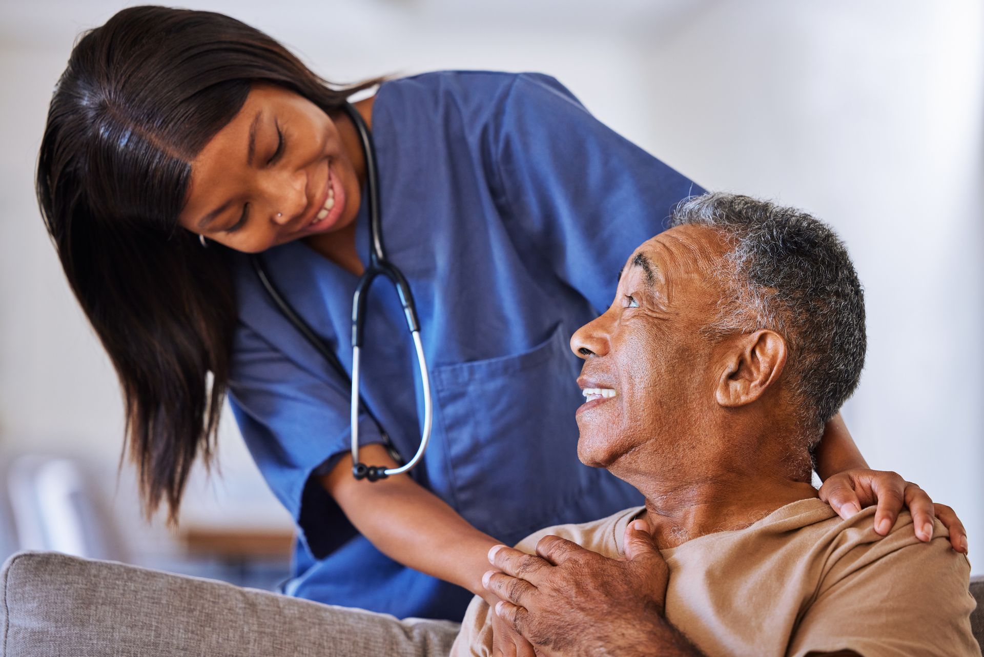 a nurse is talking to an elderly man who is sitting on a couch .