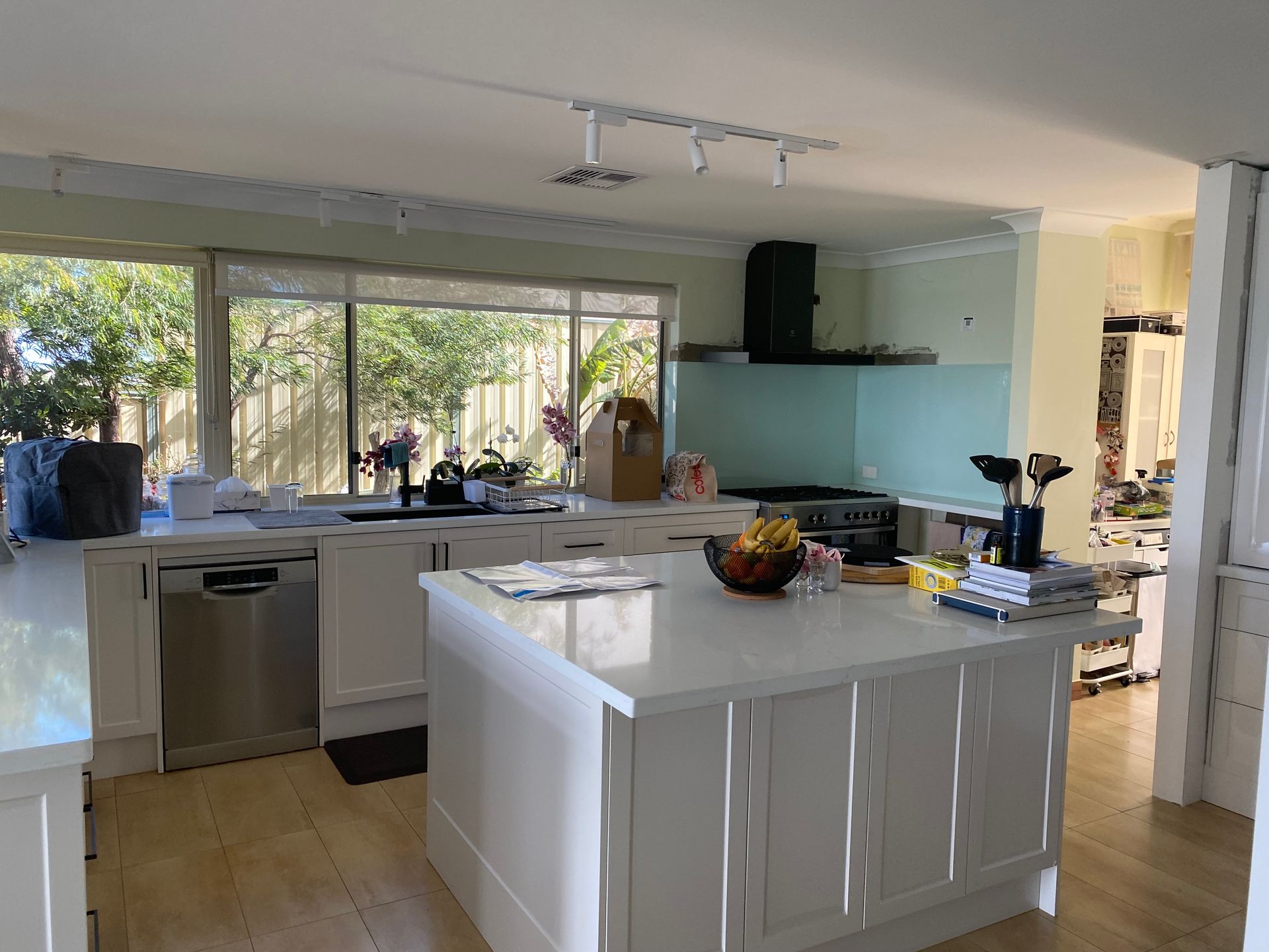 Bright kitchen with white cabinetry, island, dishwasher, stove, and large window.