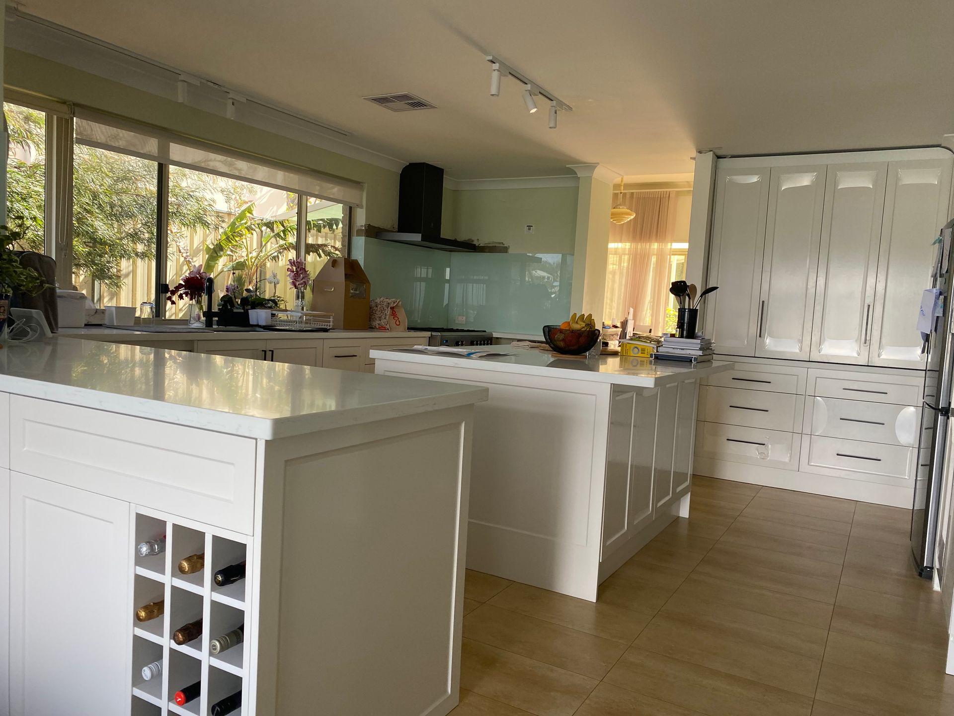 White kitchen with two islands, large windows, and a light-colored wood floor.
