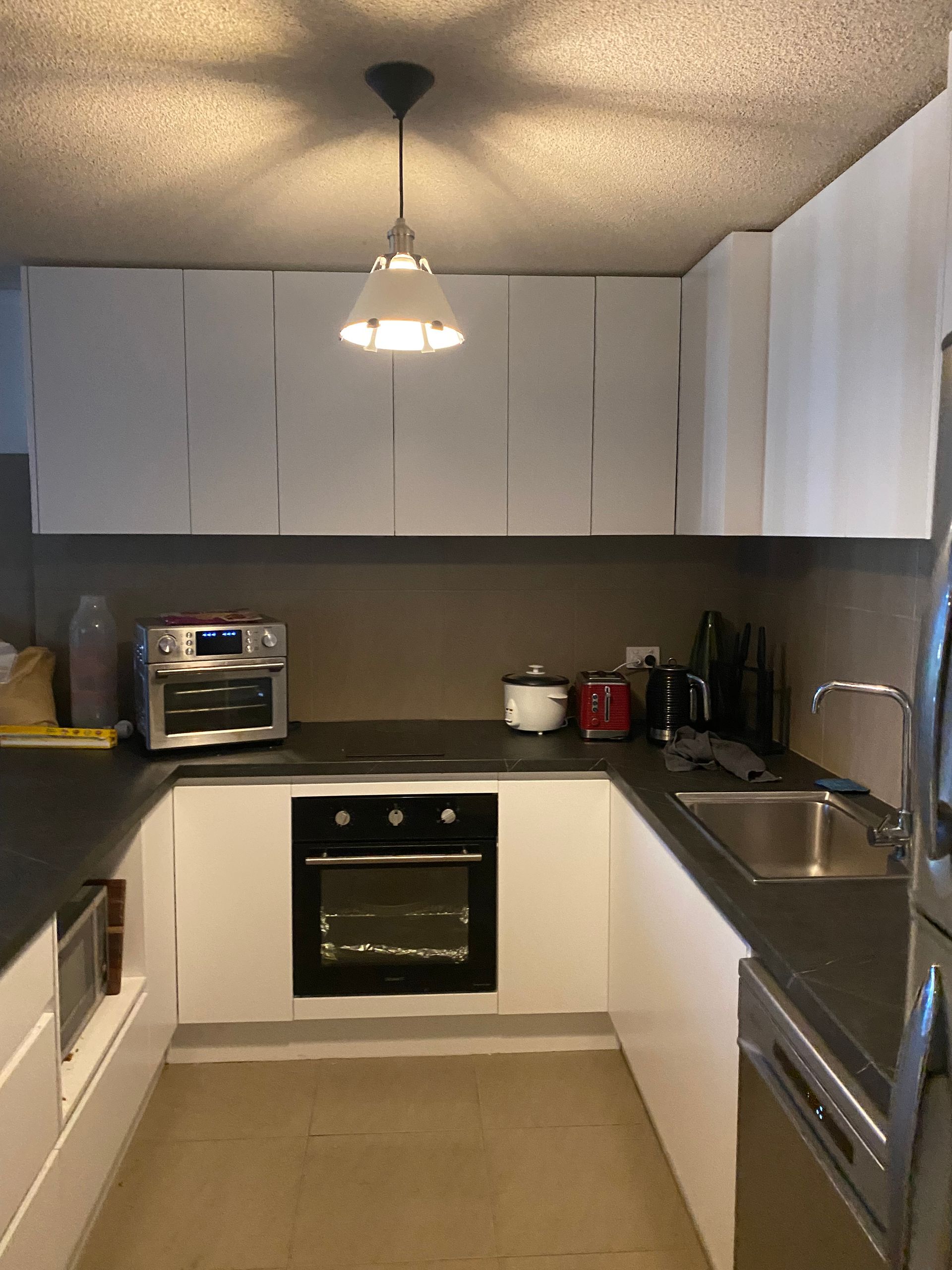 U-shaped modern kitchen with white cabinets, black countertops, and stainless steel appliances.