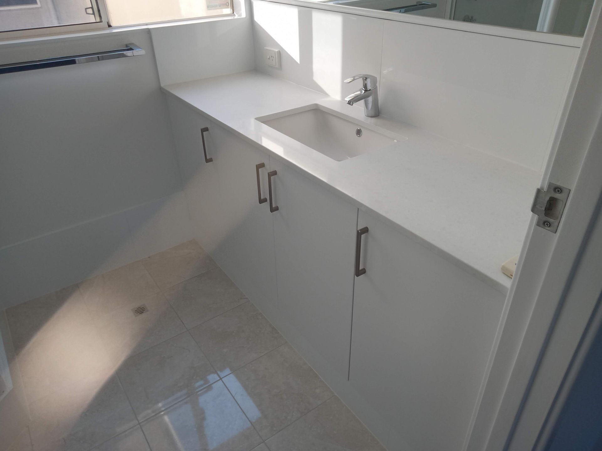 White bathroom vanity with sink, cabinets, and chrome fixtures.