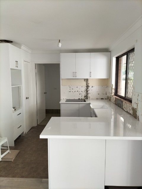 White kitchen with cabinets and countertop, partially renovated.