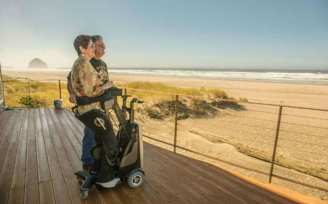 A man and a woman are standing on a deck looking at the ocean.