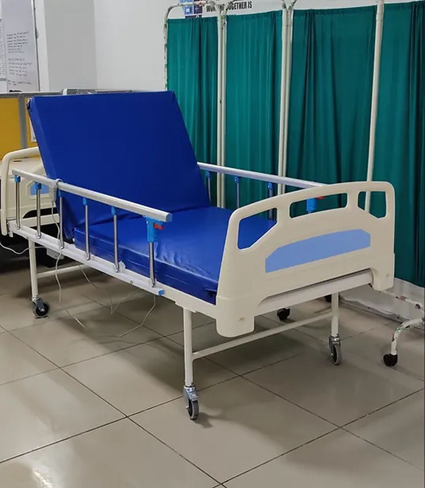 Hospital bed with blue mattress, white frame, and side rails, in a room with green curtains.