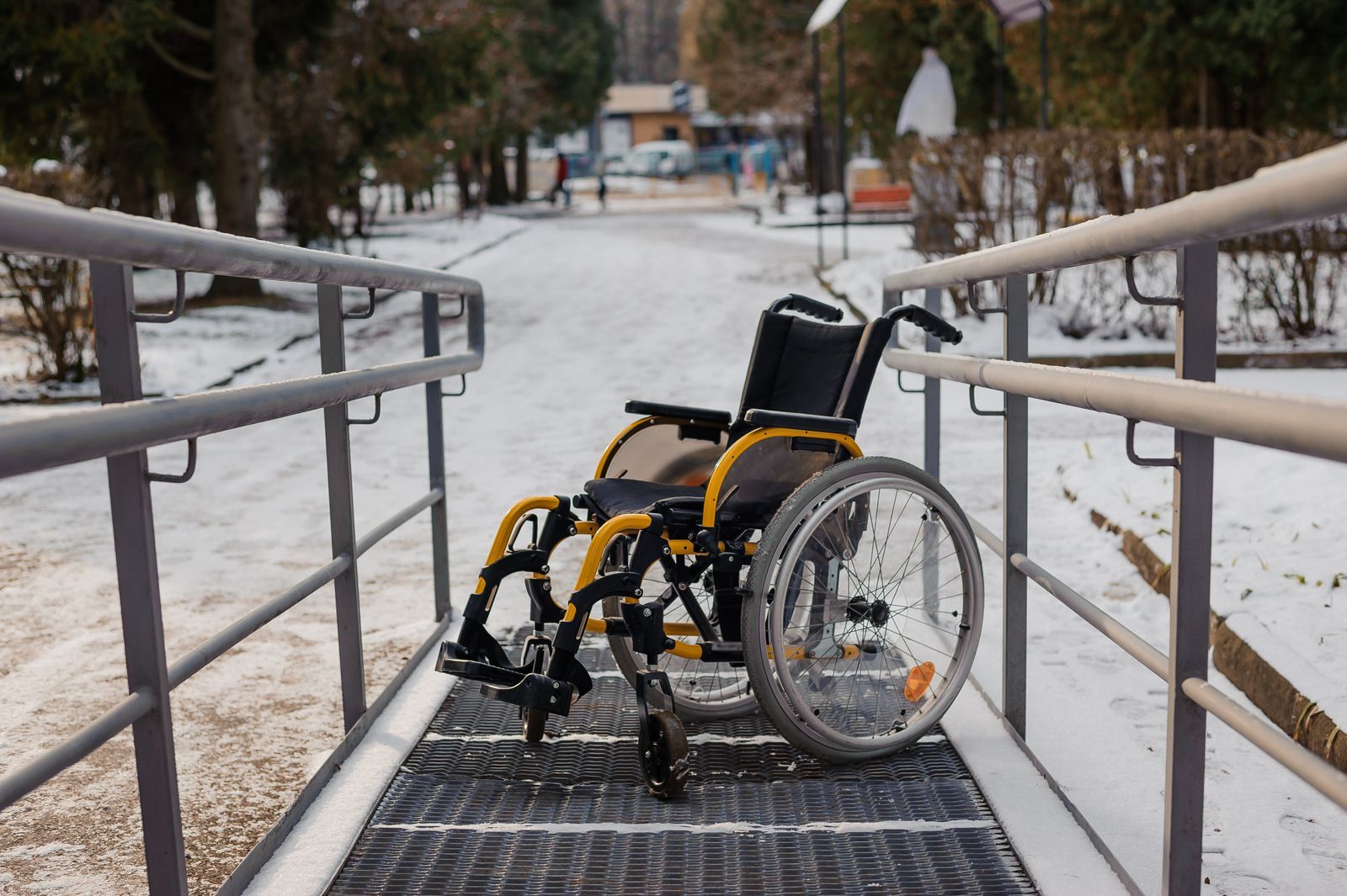 A wheelchair is parked on a ramp in the snow.