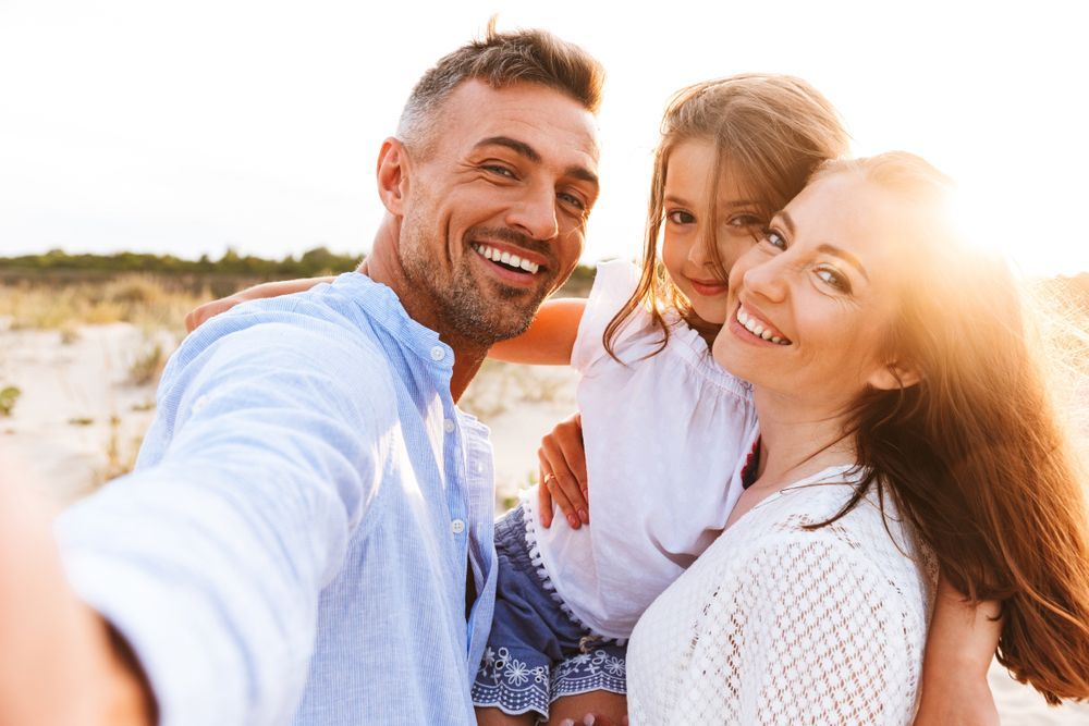 A family is taking a selfie on the beach.