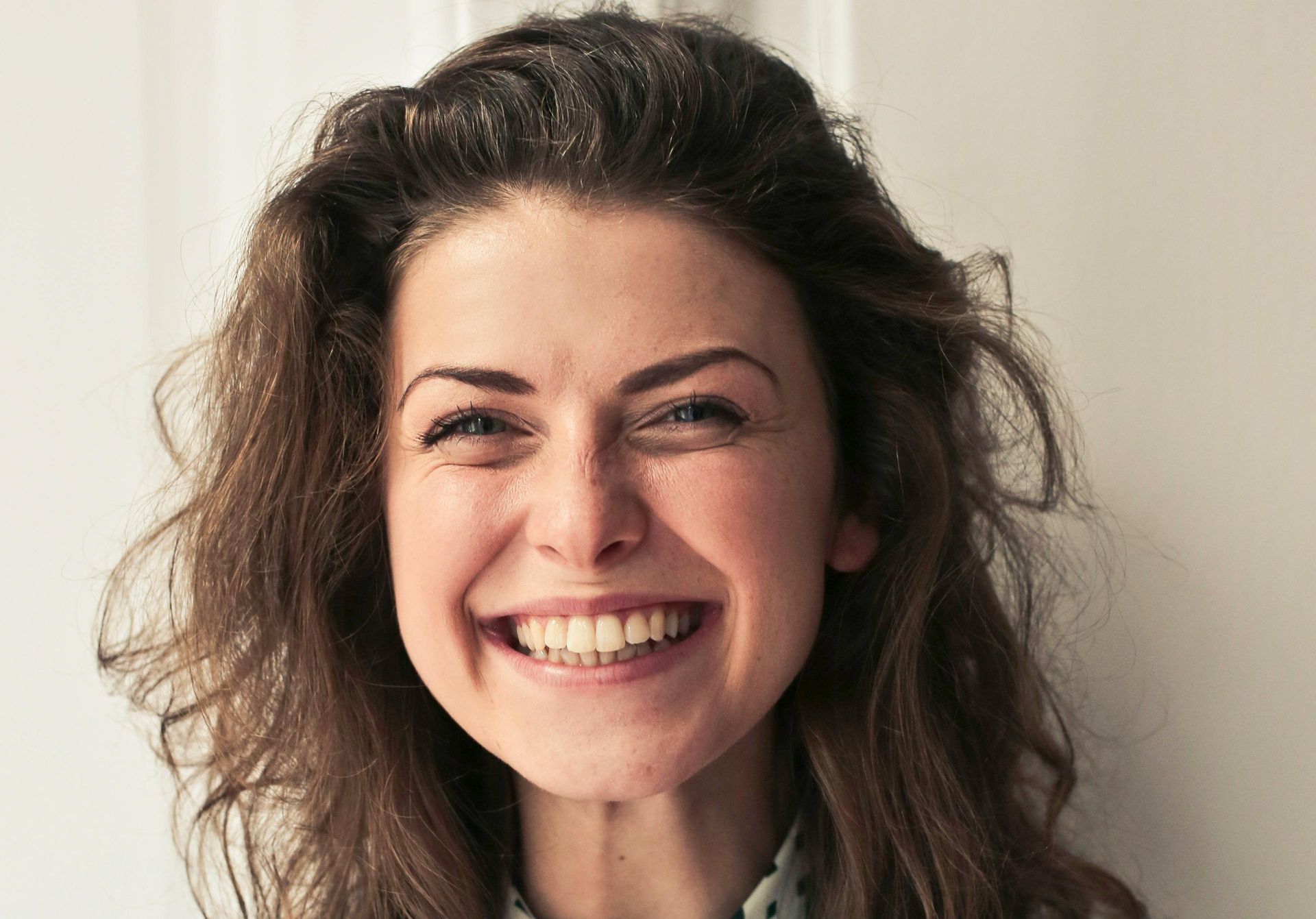 A woman with long hair is smiling and looking at the camera.