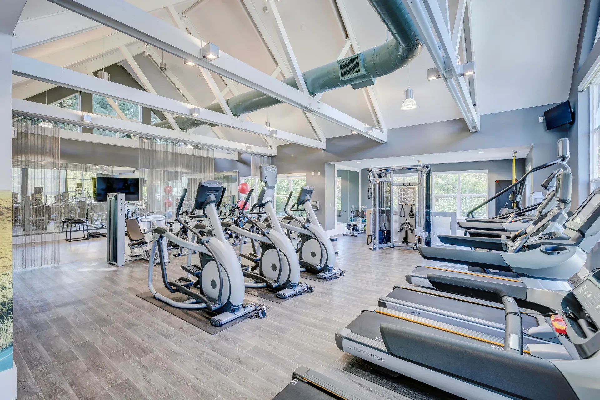 Bright modern community gym with treadmills, ellipticals, and weight machines.