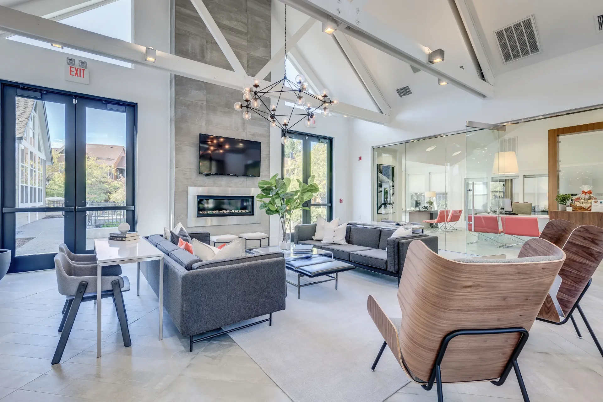 Modern resident lounge with fireplace, TV, and glass-walled seating area.