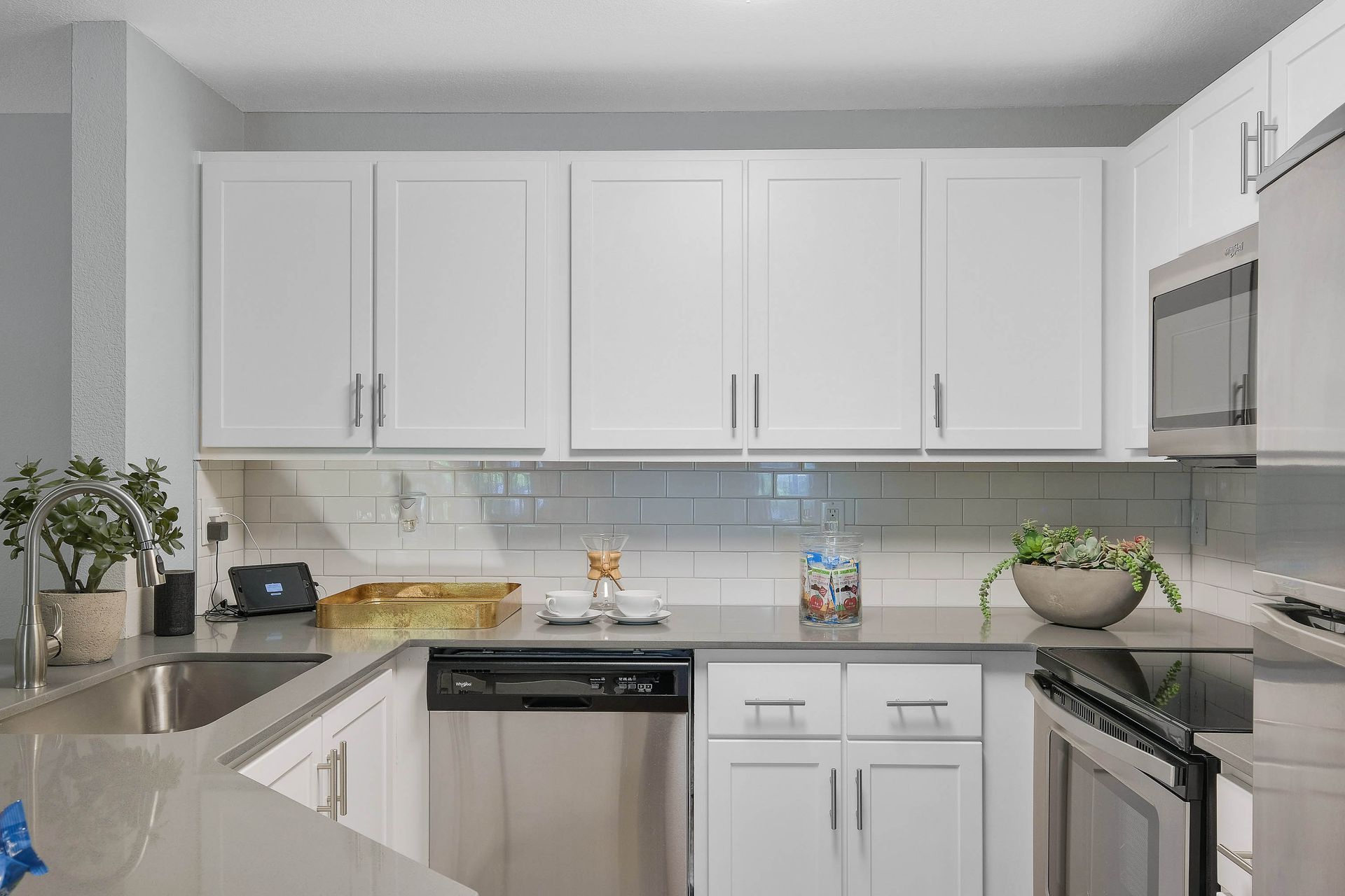 White kitchen with white cabinets, stainless steel appliances, subway tile backsplash, and granite countertops.