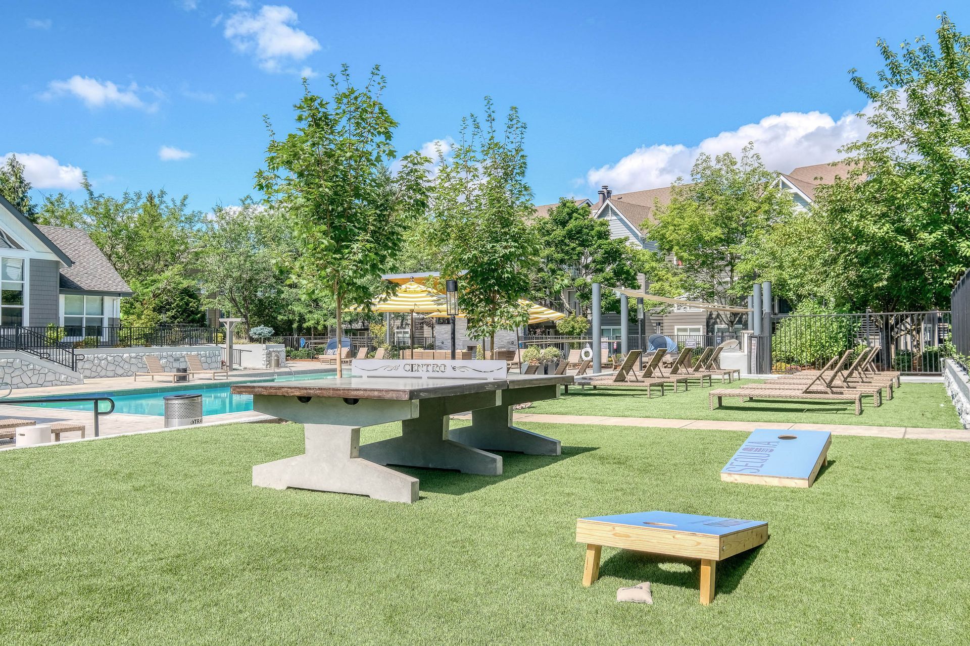 Outdoor community pool area with lounge chairs and a large ping-pong table.