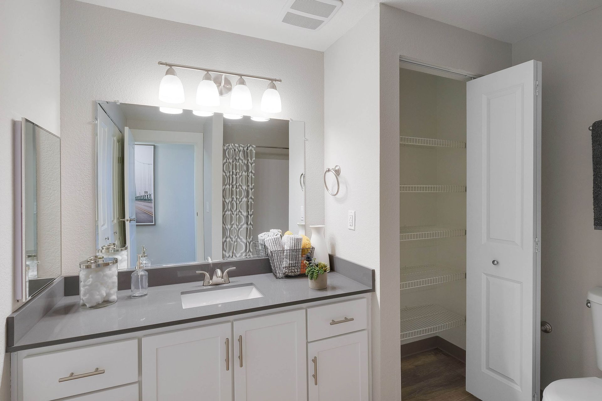Bathroom vanity with sink, mirror, and an open closet with wire shelves.