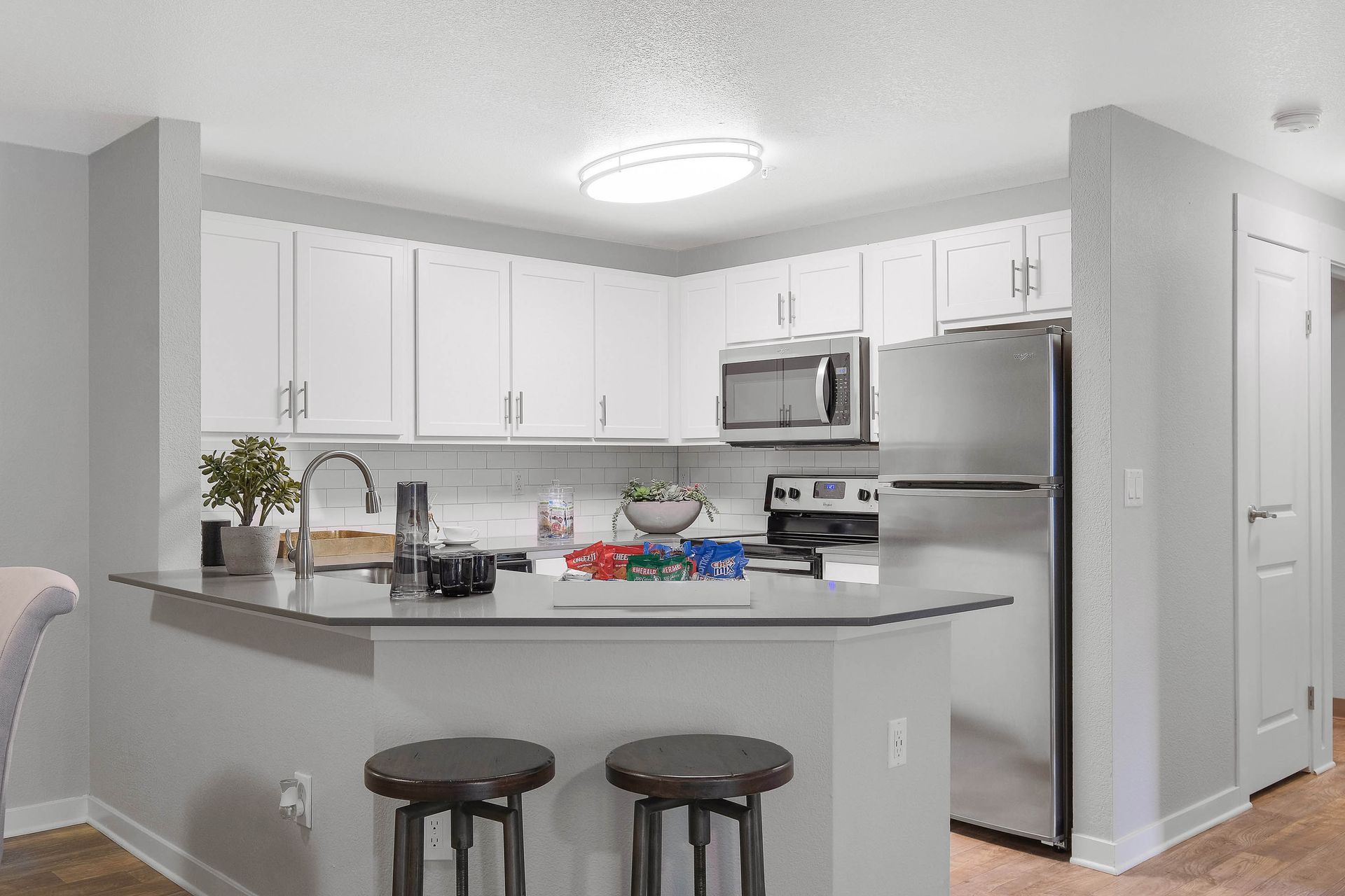 Bright apartment kitchen with white cabinets, stainless steel appliances, and a central island.