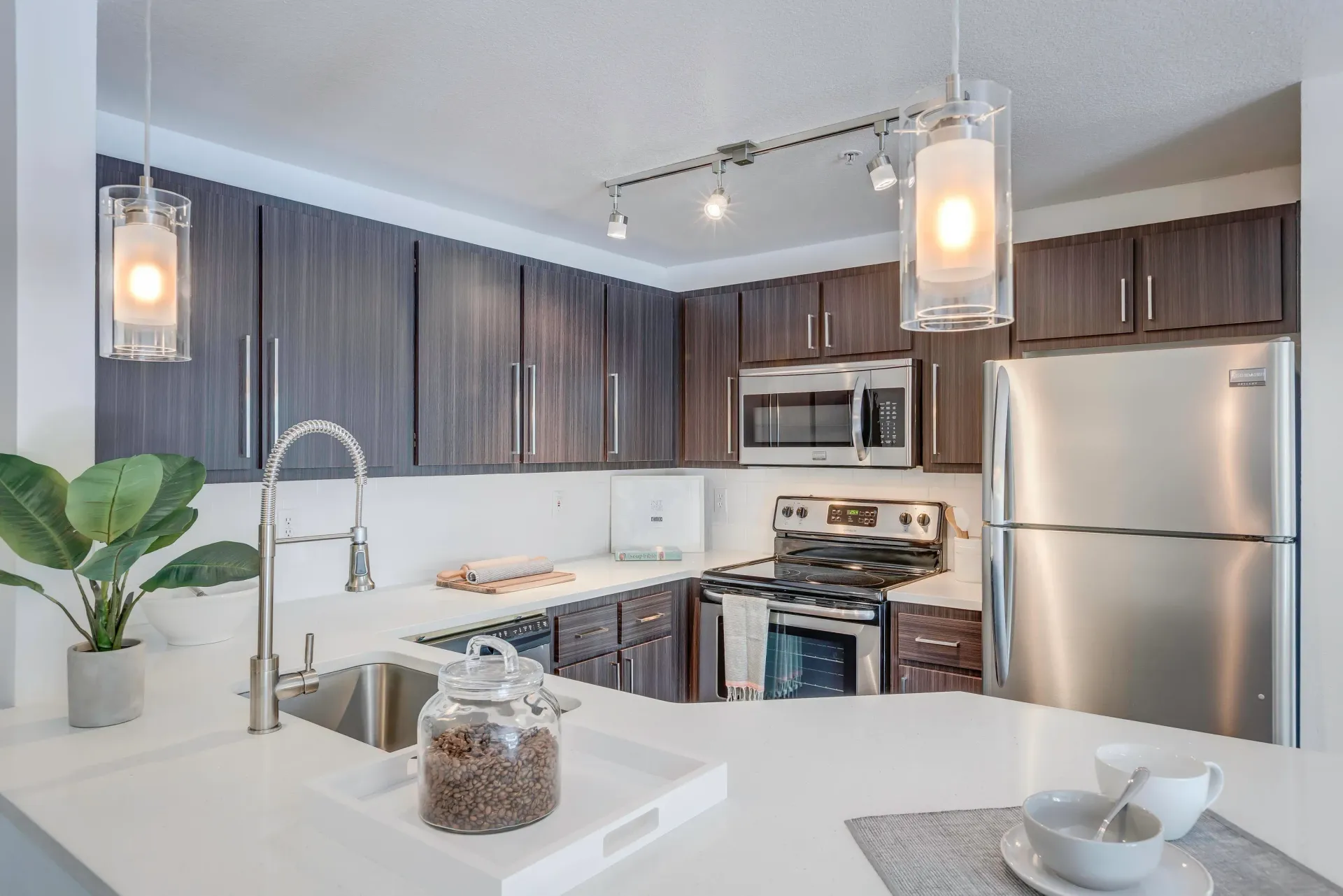 Modern kitchen with dark wood cabinets, stainless steel appliances, and white quartz countertops.
