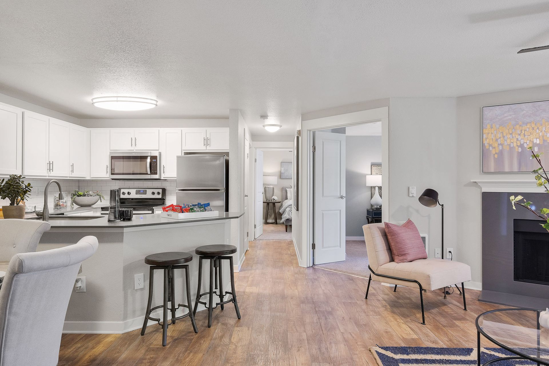 Open-concept kitchen and living area with white cabinets, stainless appliances, island, and seating.