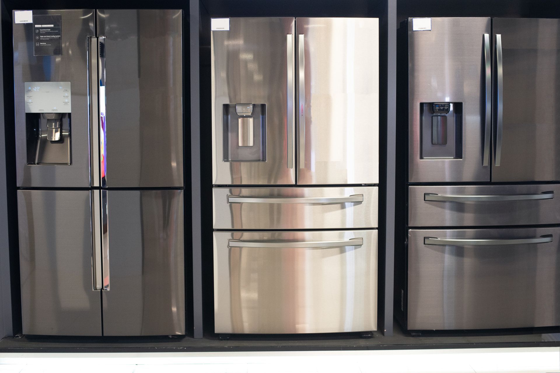 A row of stainless steel refrigerators on display in a store.