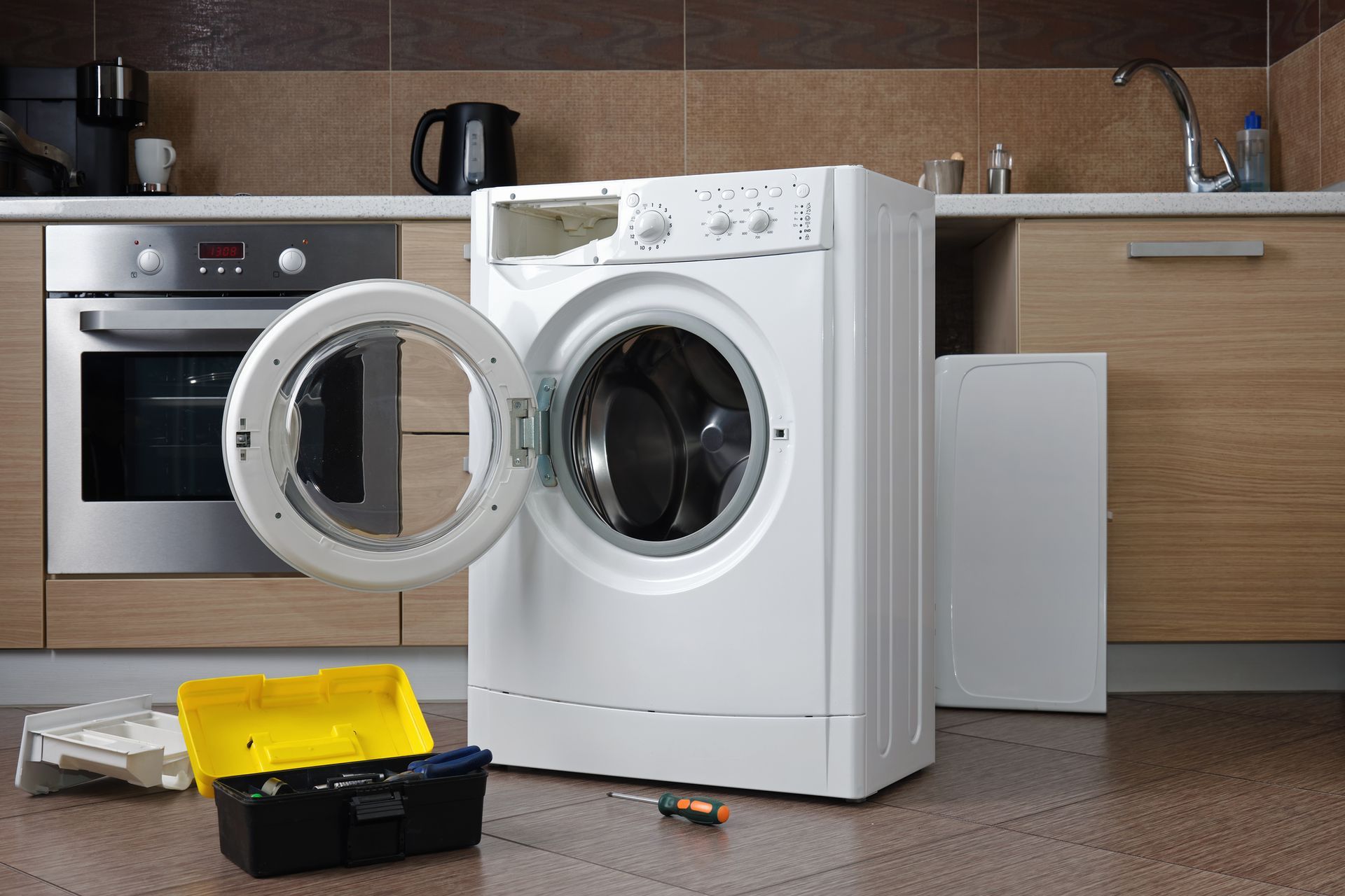 A washing machine is being repaired in a kitchen.