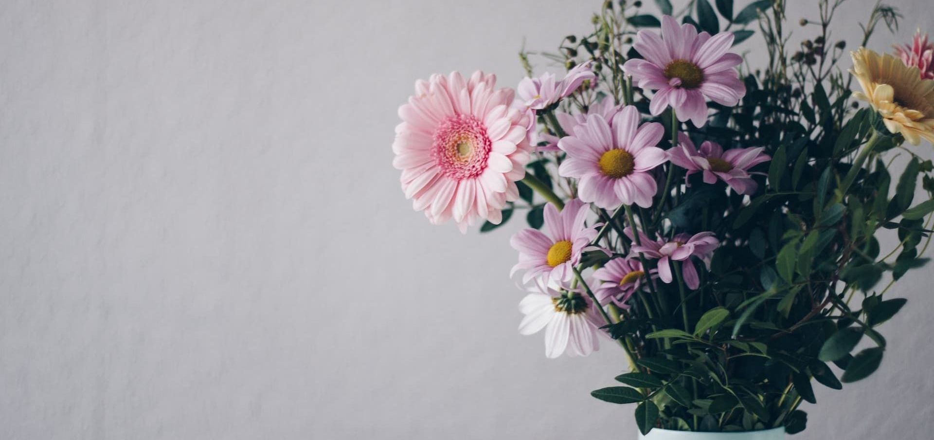 A bouquet of pink and yellow flowers in a vase on a table.