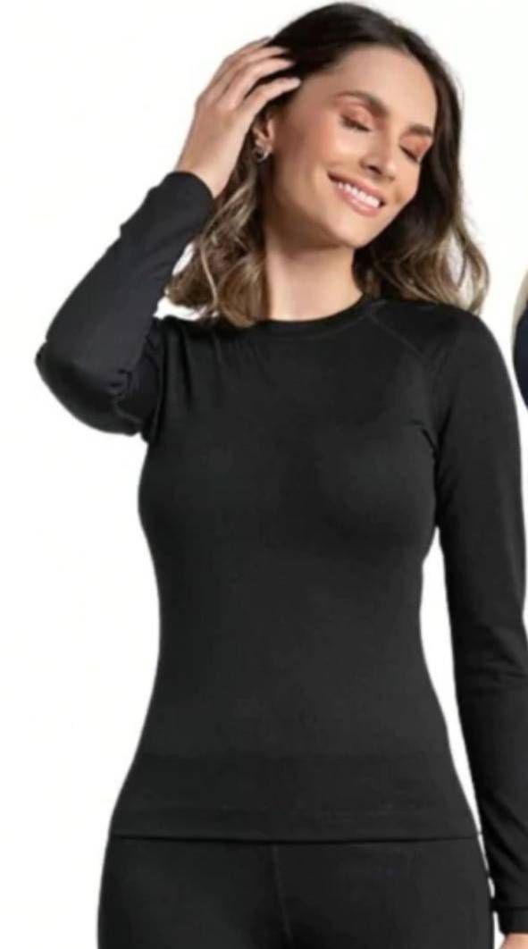 Una mujer lleva una camisa de manga larga negra y pantalones negros.