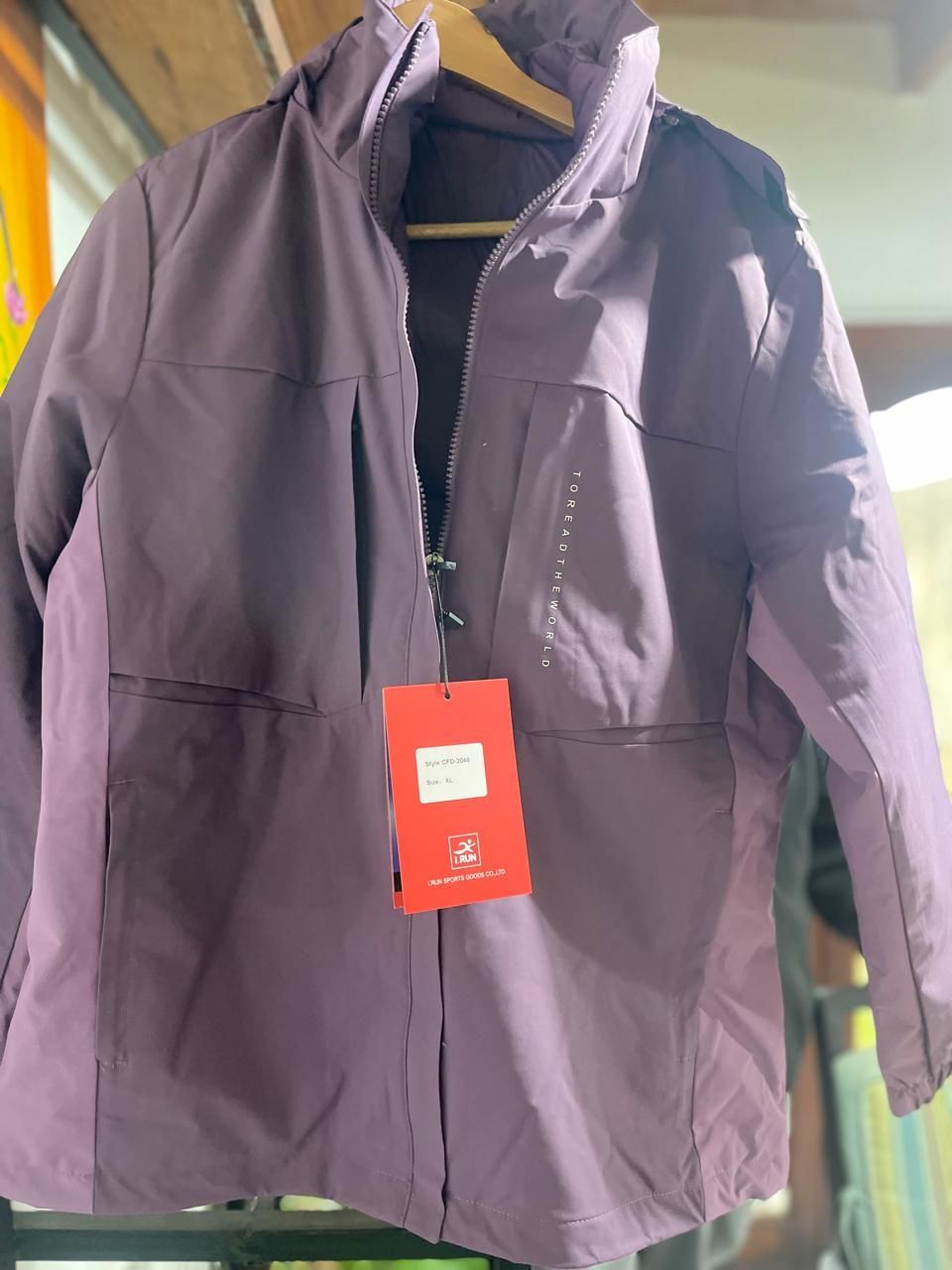 Una chaqueta morada con una etiqueta está colgada en una percha.