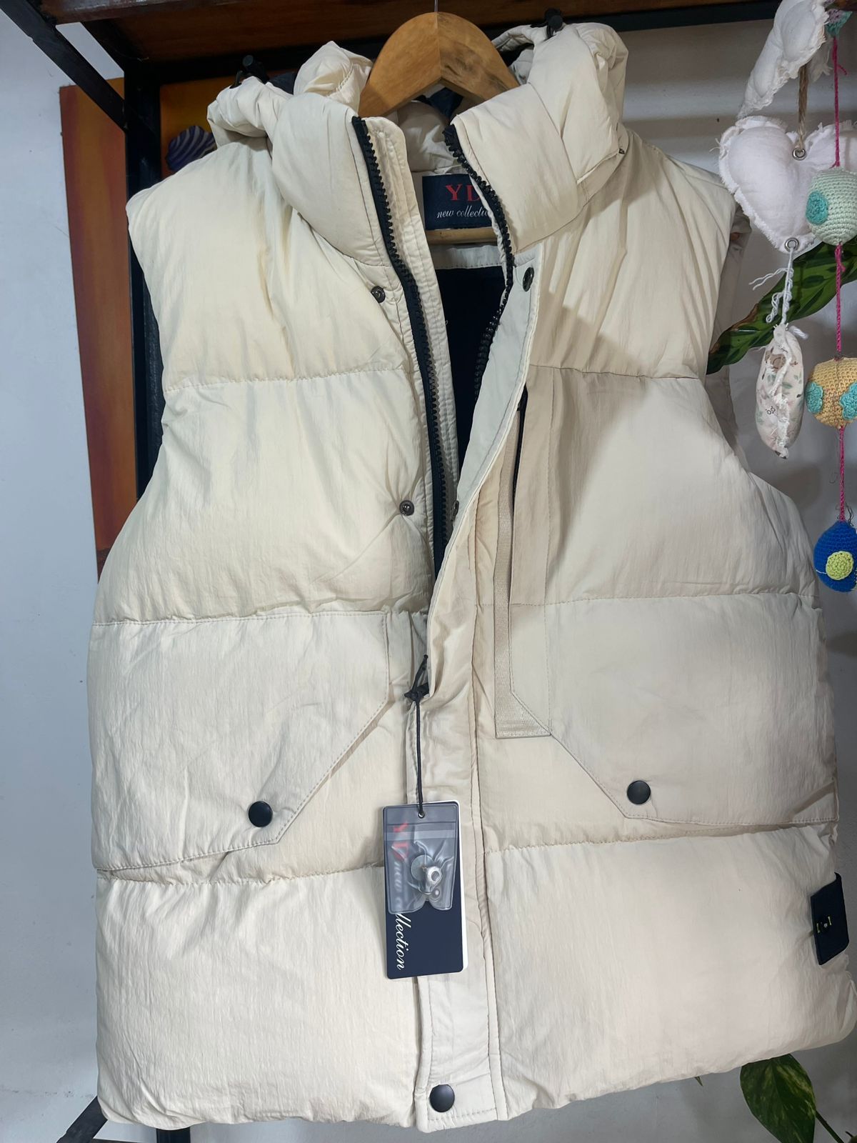 Un chaleco blanco con capucha está colgado en una percha.