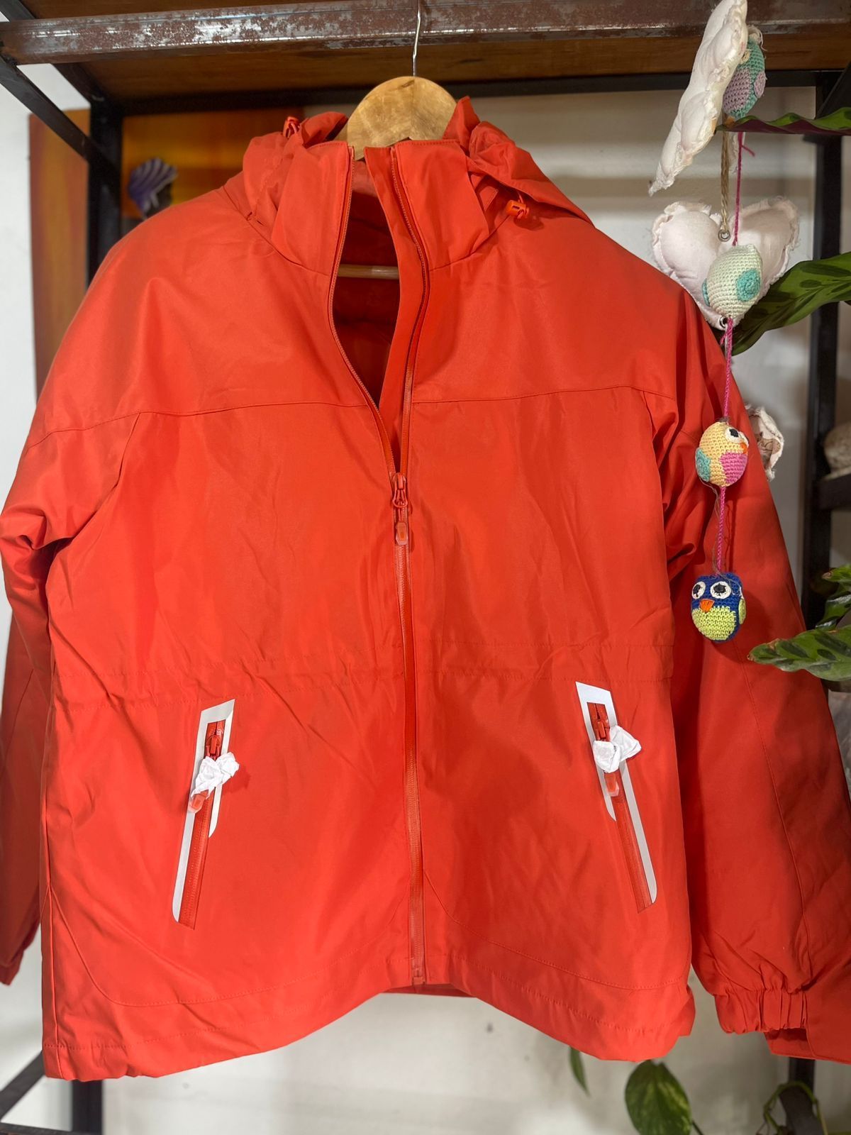 Una chaqueta roja con capucha está colgada en una percha
