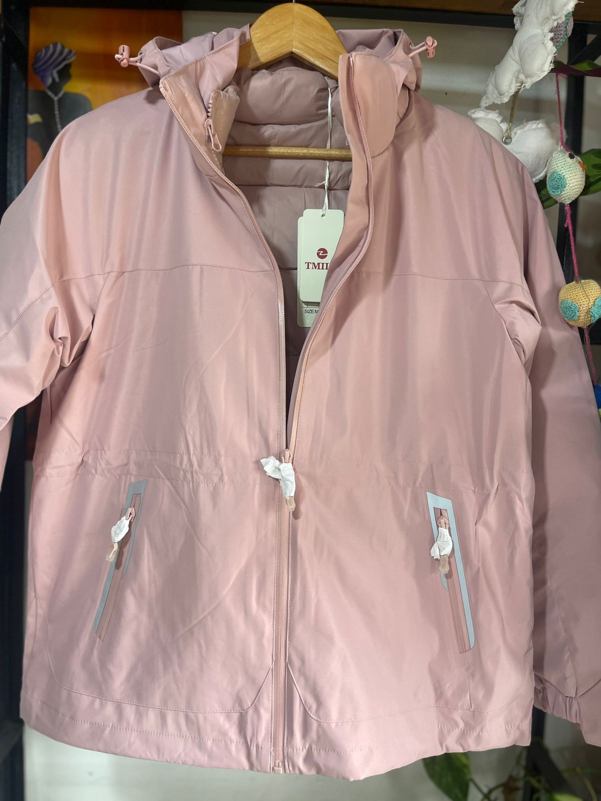 Una chaqueta rosa con capucha está colgada en una percha.
