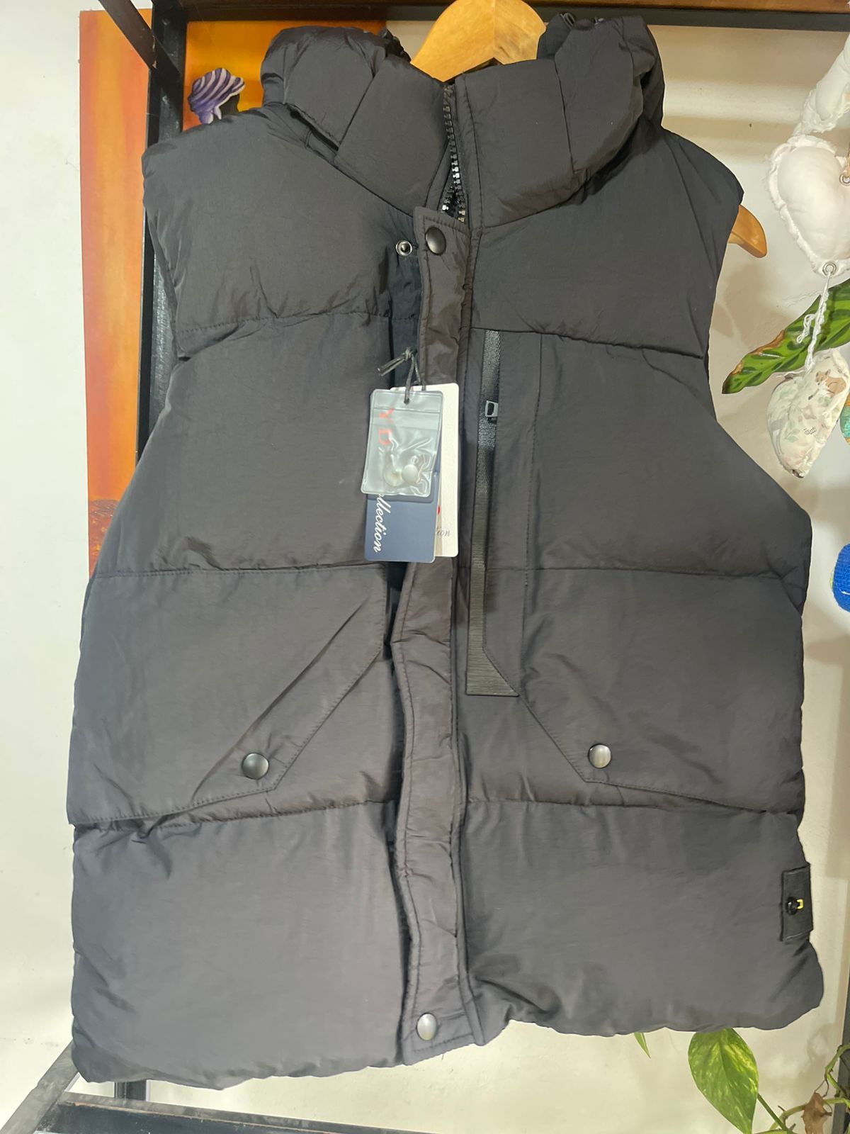 Un chaleco negro con capucha está colgado en una percha.