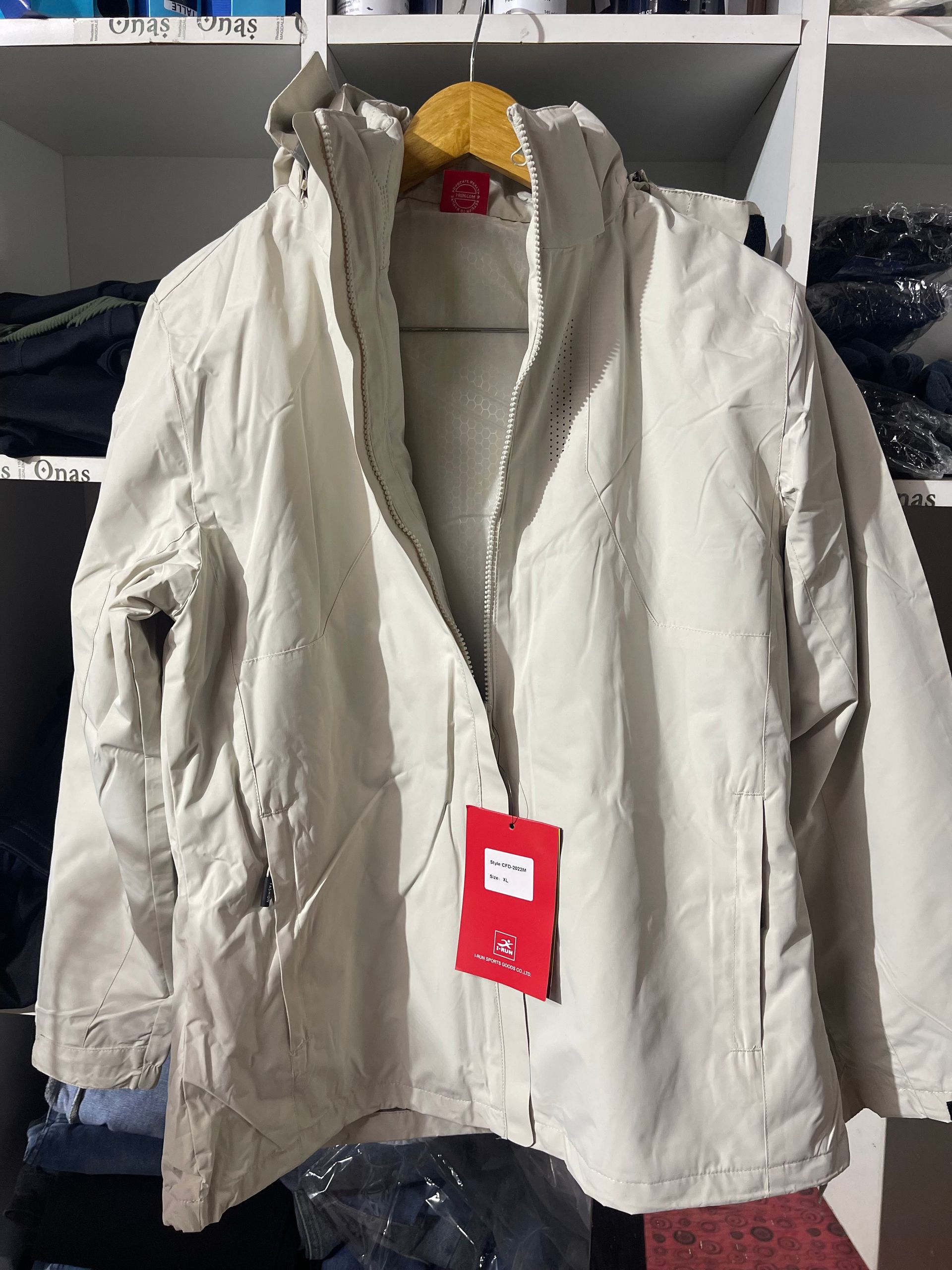 Una chaqueta blanca con una etiqueta roja está colgada en una percha