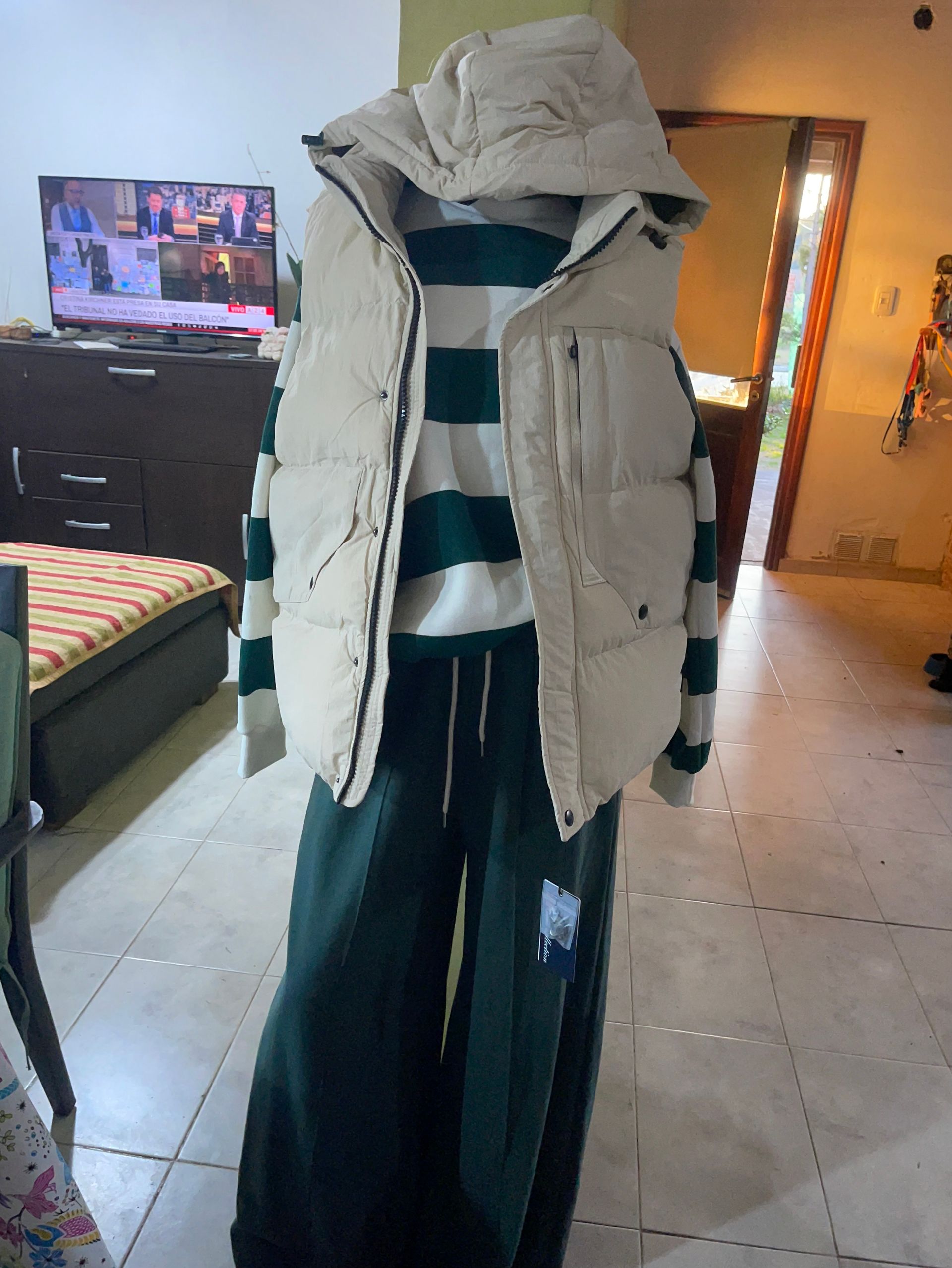 Un maniquí con un chaleco blanco y un suéter de rayas verdes.