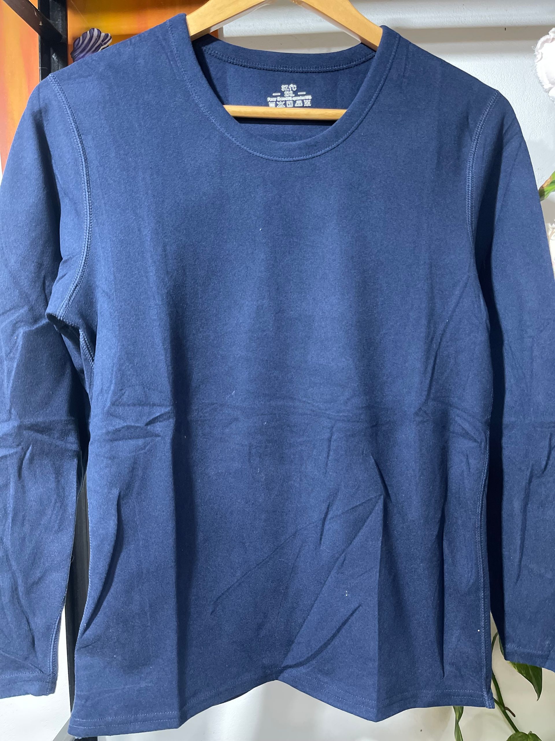 Una camisa azul con mangas largas está colgada en una percha.