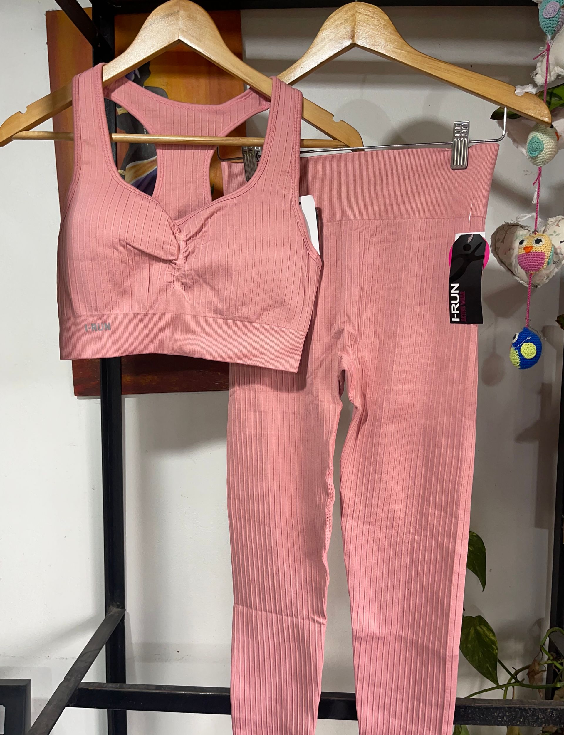 Un top corto rosa y unas mallas cuelgan de un perchero.
