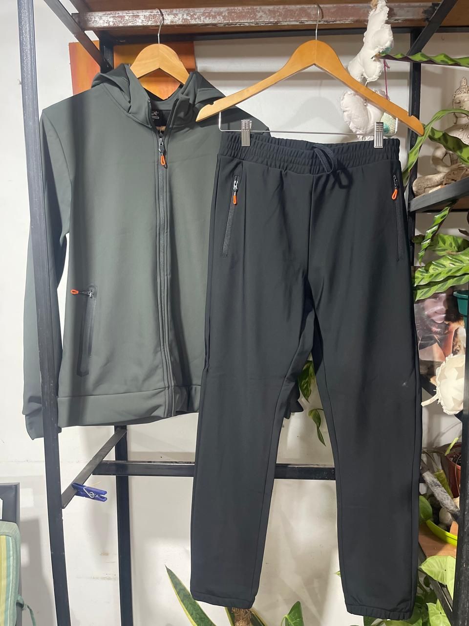 Una chaqueta verde y unos pantalones negros cuelgan de un perchero.