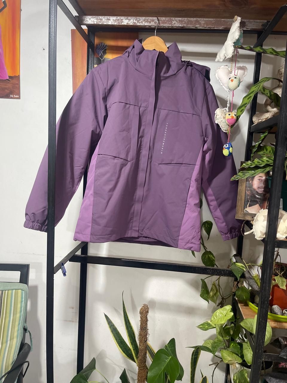 Una chaqueta morada está colgada en un perchero en una habitación.
