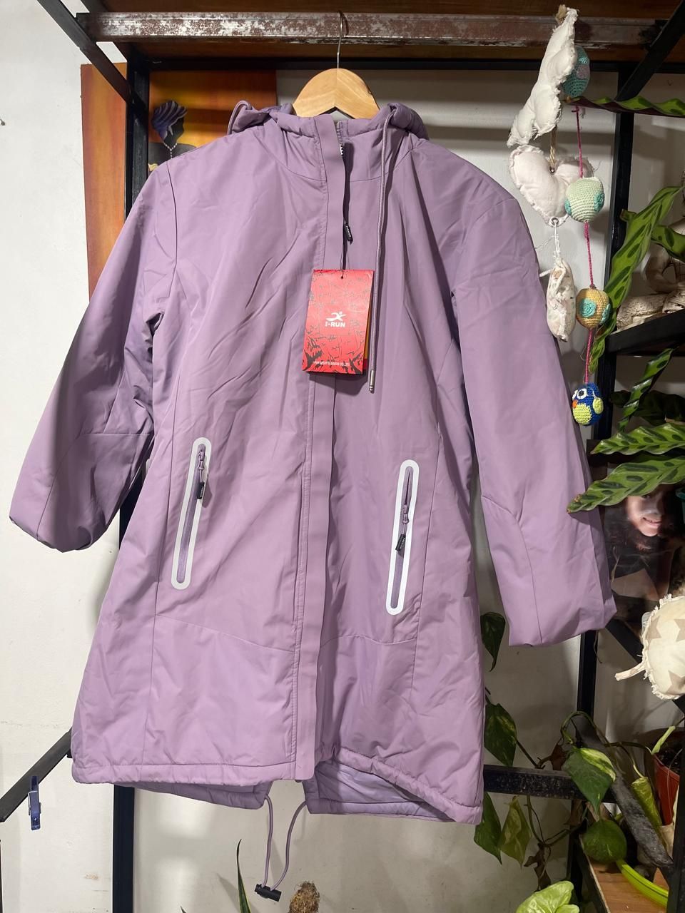 Una chaqueta morada con capucha está colgada en una percha.