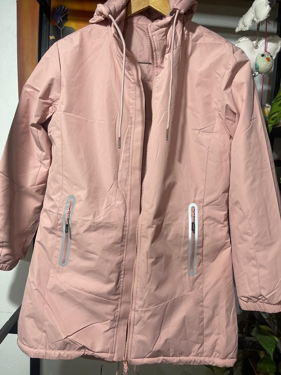 Una chaqueta rosa con capucha está colgada en una percha.