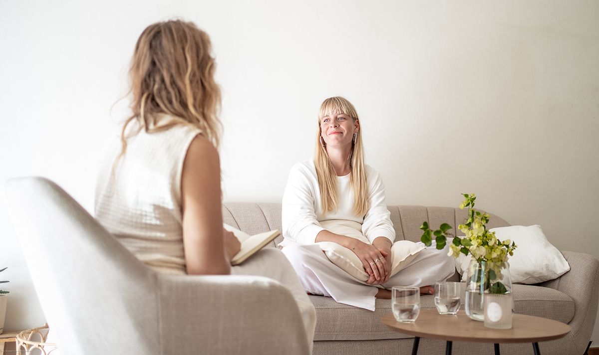 Zwei weibliche Personen sitzen in einer hellen Praxis und führen ein Gespräch.