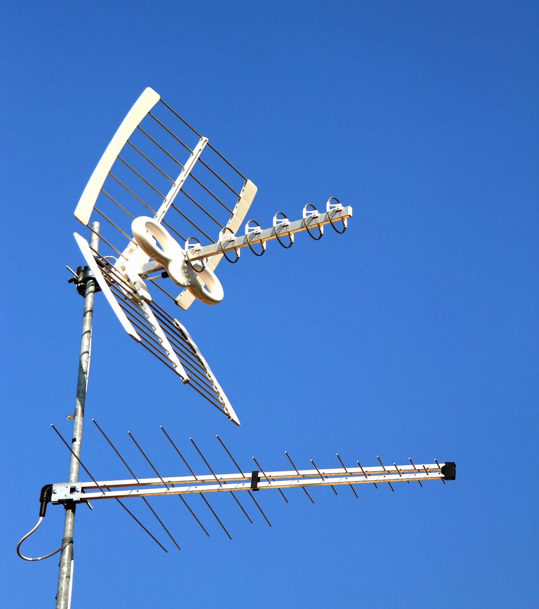 Due antenne televisive sul tetto, stagliate contro un cielo azzurro e limpido.