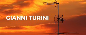 White “GIANNI TURINI” text beside a black construction crane silhouette on an orange background