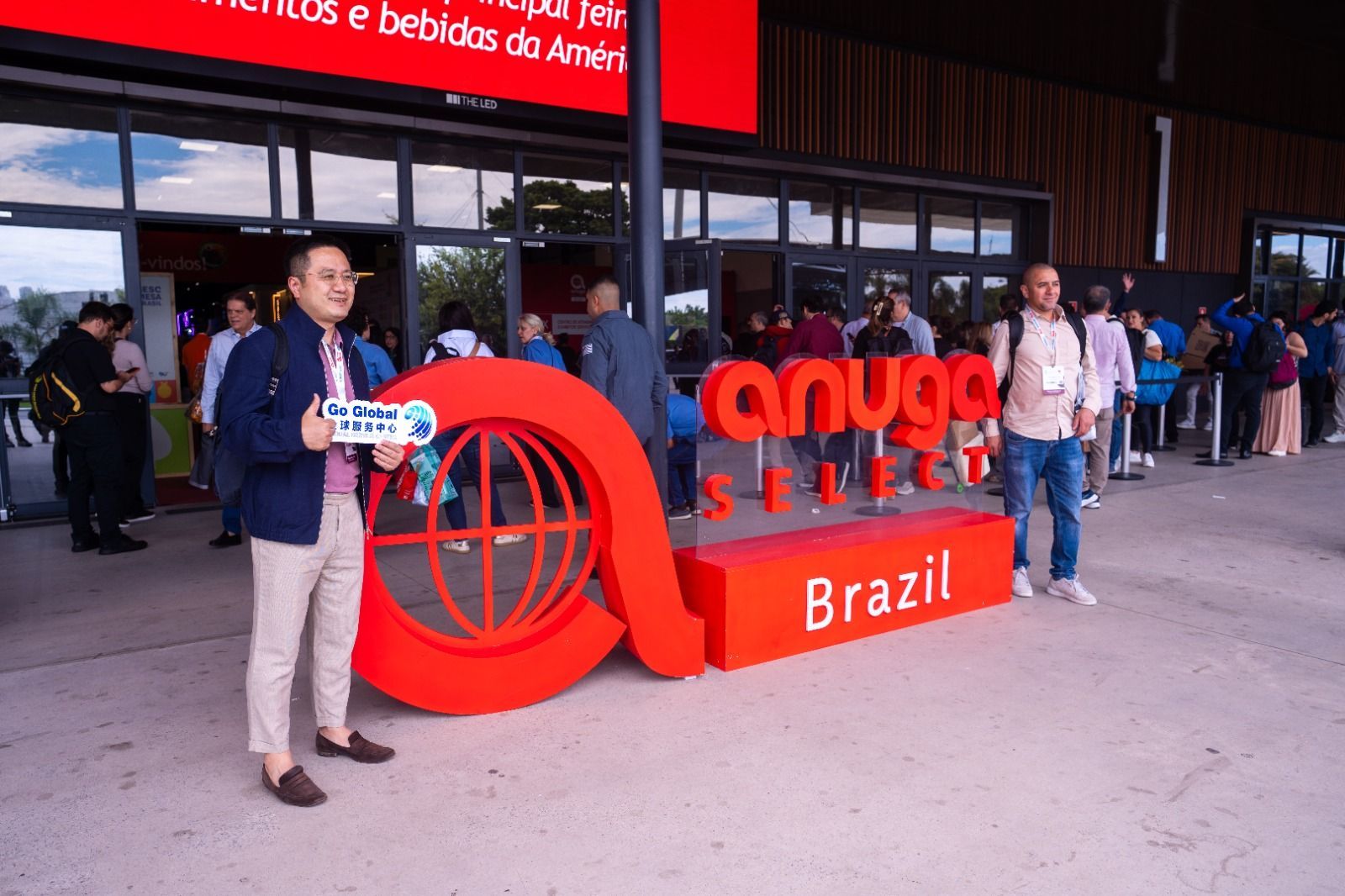 Homem segurando um microfone, falando para uma plateia. Ele está vestindo uma camisa preta.