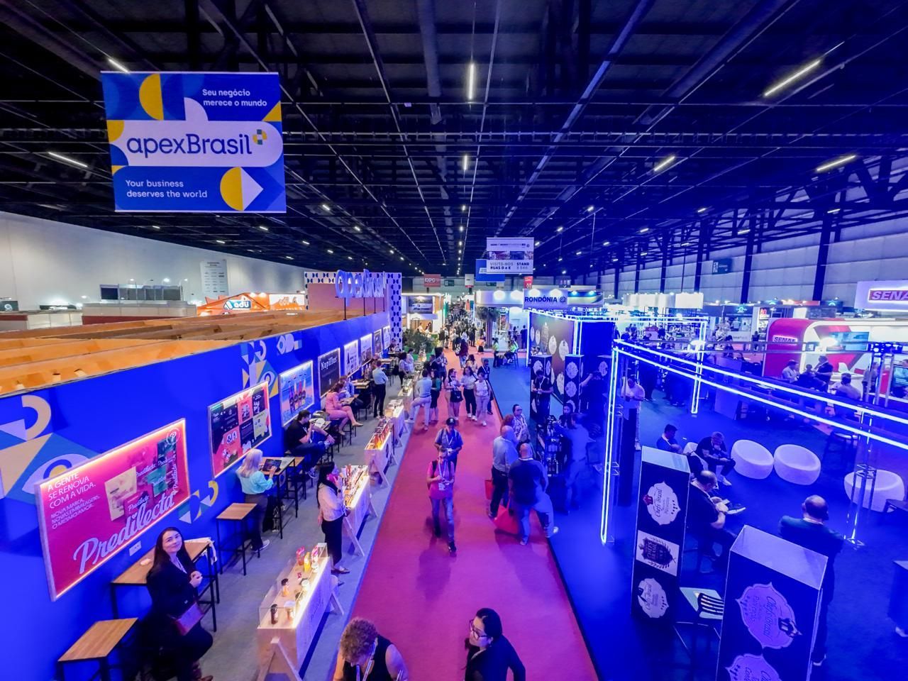 Homem discursando em uma conferência. Texto na tela: