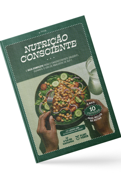 Homem de camisa preta falando ao microfone, segurando um controle remoto, com um cenário de palco ao fundo.
