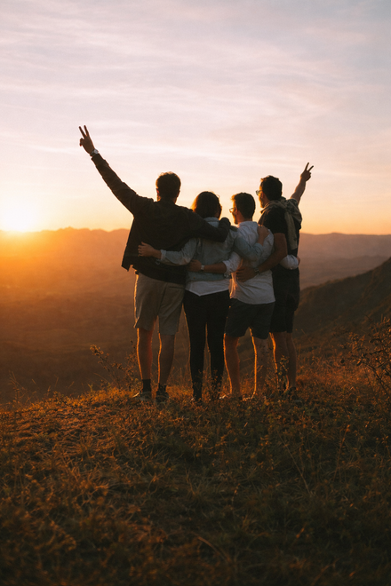 Homem de camisa preta falando ao microfone, segurando um controle remoto, com um cenário de palco ao fundo.