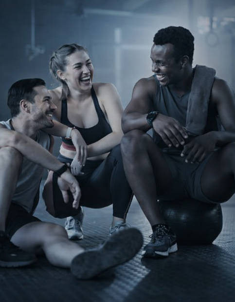 Três pessoas rindo em uma academia após o treino.