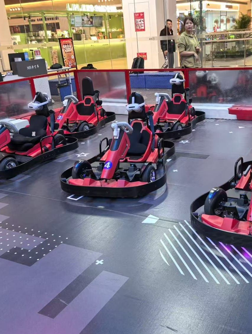 Carrinhos de kart vermelhos enfileirados em uma pista dentro de um prédio.