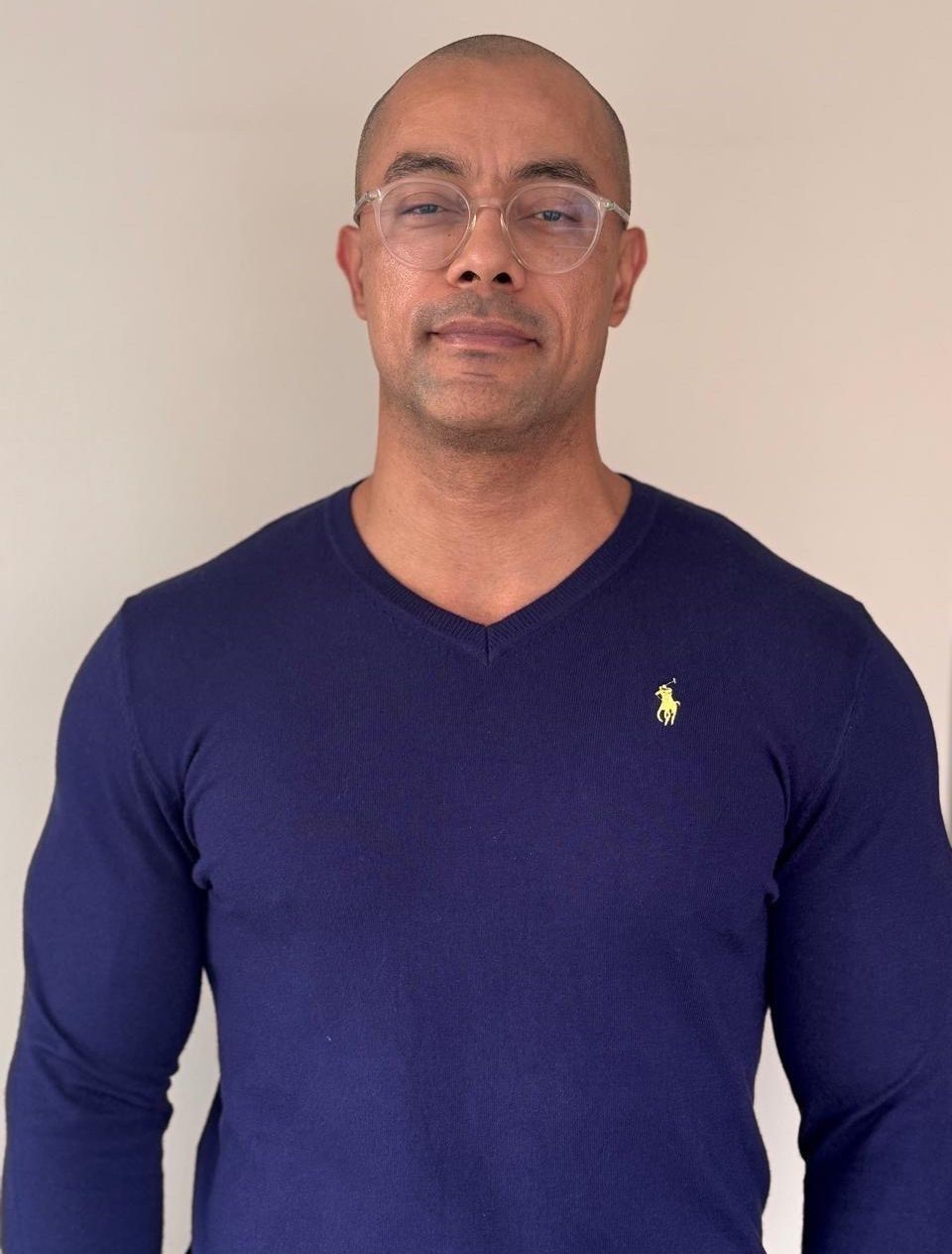 Homem segurando um microfone, falando para uma plateia. Ele está vestindo uma camisa preta.