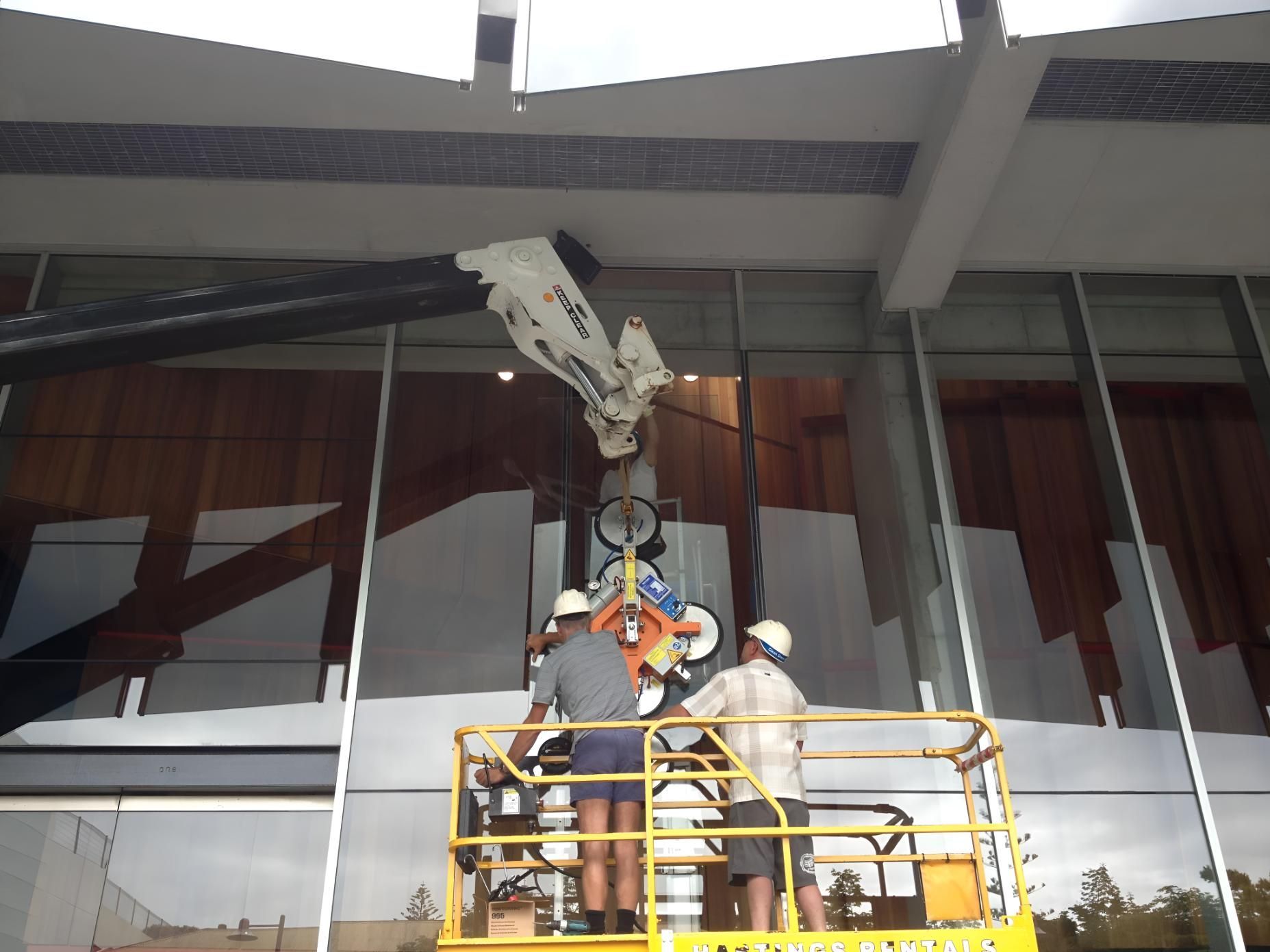 A Group Of Construction Workers Are Working On A Large Building — Pavy's Glass In Port Macquarie, NSW
